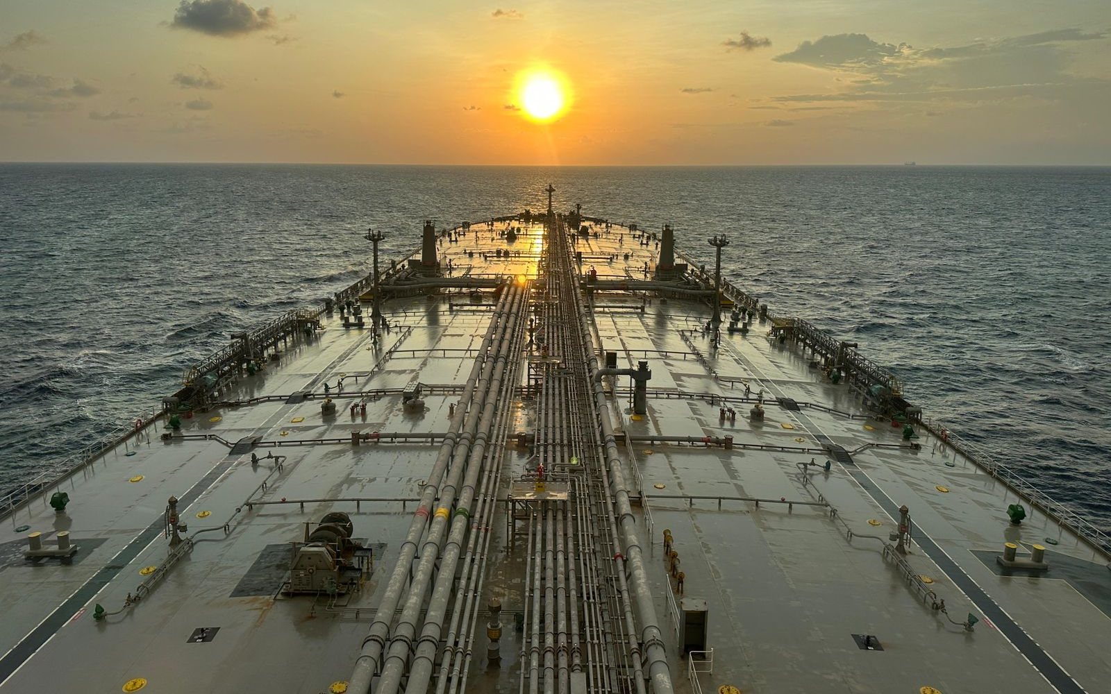 View along a tanker's deck towards the sunrise at sea
